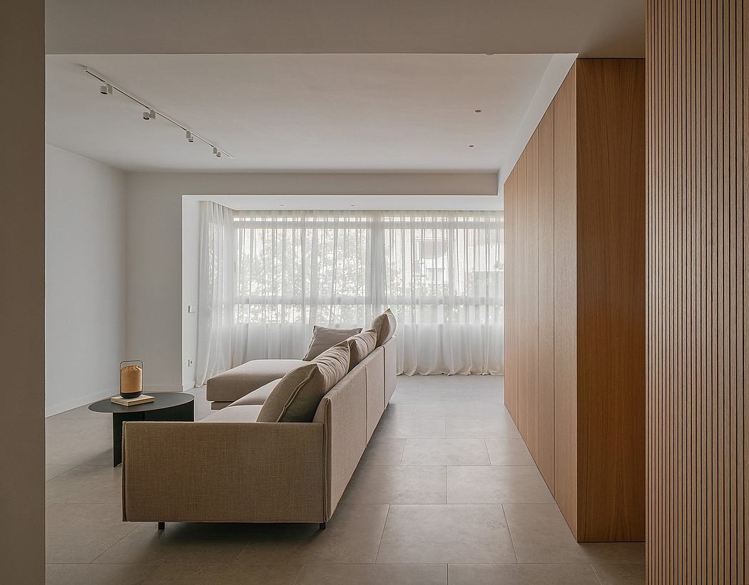 Modern minimalist living room with neutral tones, large windows, and wooden accents.