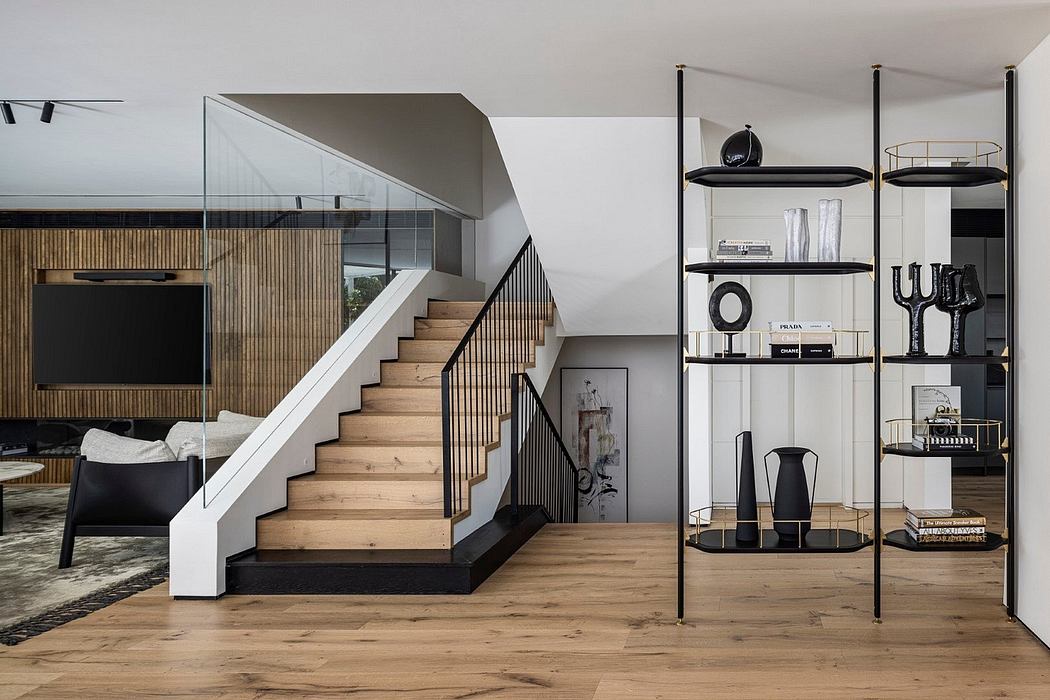 Sleek, modern staircase with warm wood treads and minimalist black handrails. Stylish shelving unit with decorative objects.