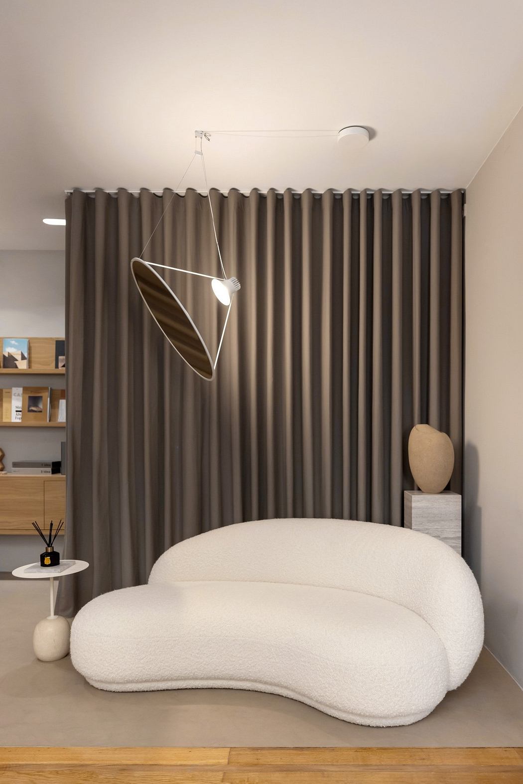 A modern cozy living space with a plush white sofa, statement lighting, and sleek shelving.