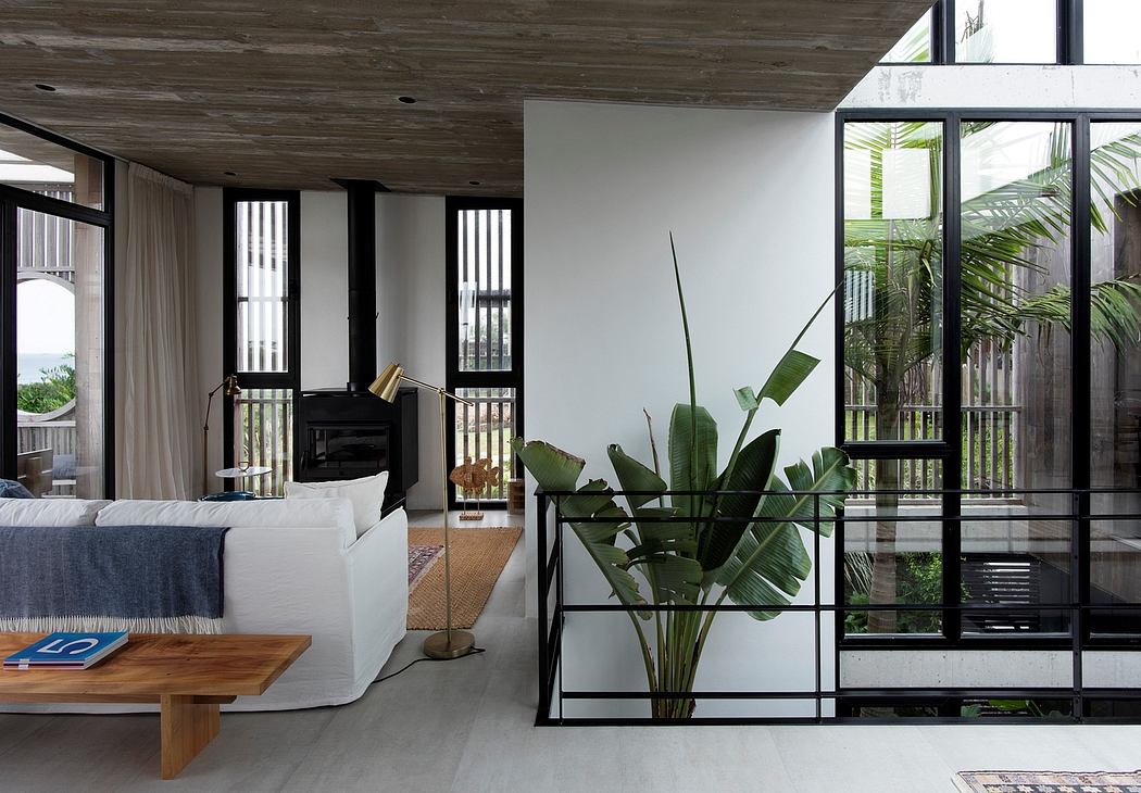 Spacious open-plan living area with large windows, wood-paneled ceiling, and tropical plants.