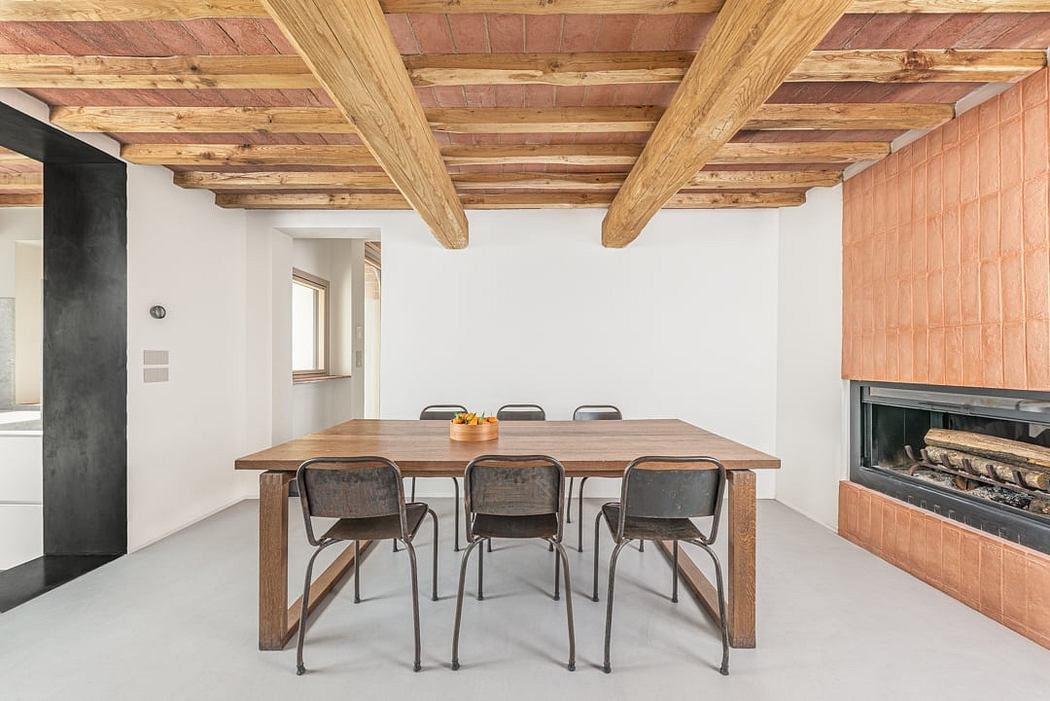 Rustic wooden ceiling beams and brick fireplace in minimalist dining room.