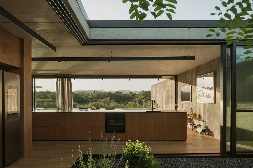 Spacious open-plan kitchen with seamless indoor-outdoor connection and verdant panoramic view.