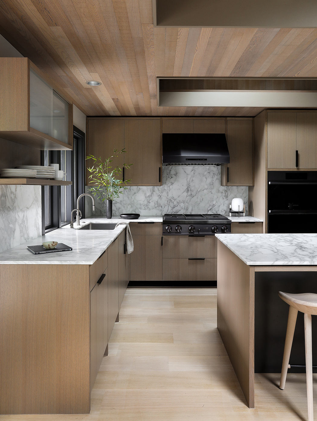 Sleek modern kitchen with wooden cabinets, marble countertops, and stainless steel appliances.