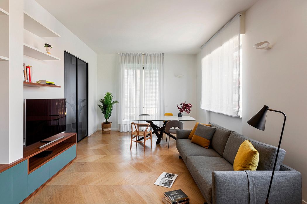 Minimalist living room with wood floors, colorful furniture, and large windows.