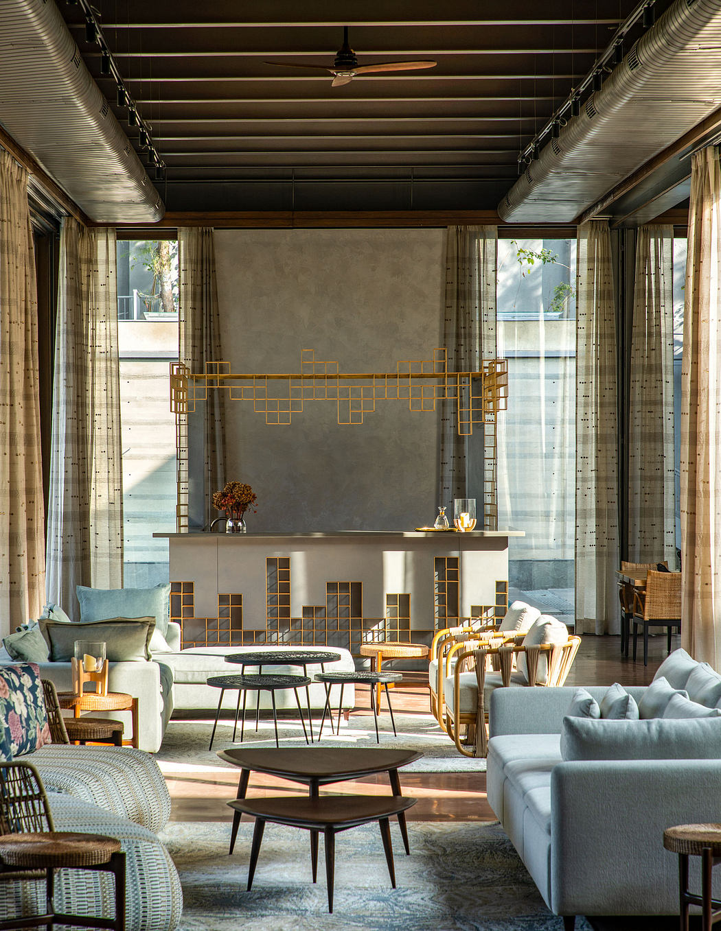 Modern, open-plan living space with concrete walls, wood-beamed ceiling, and geometric metal decor.