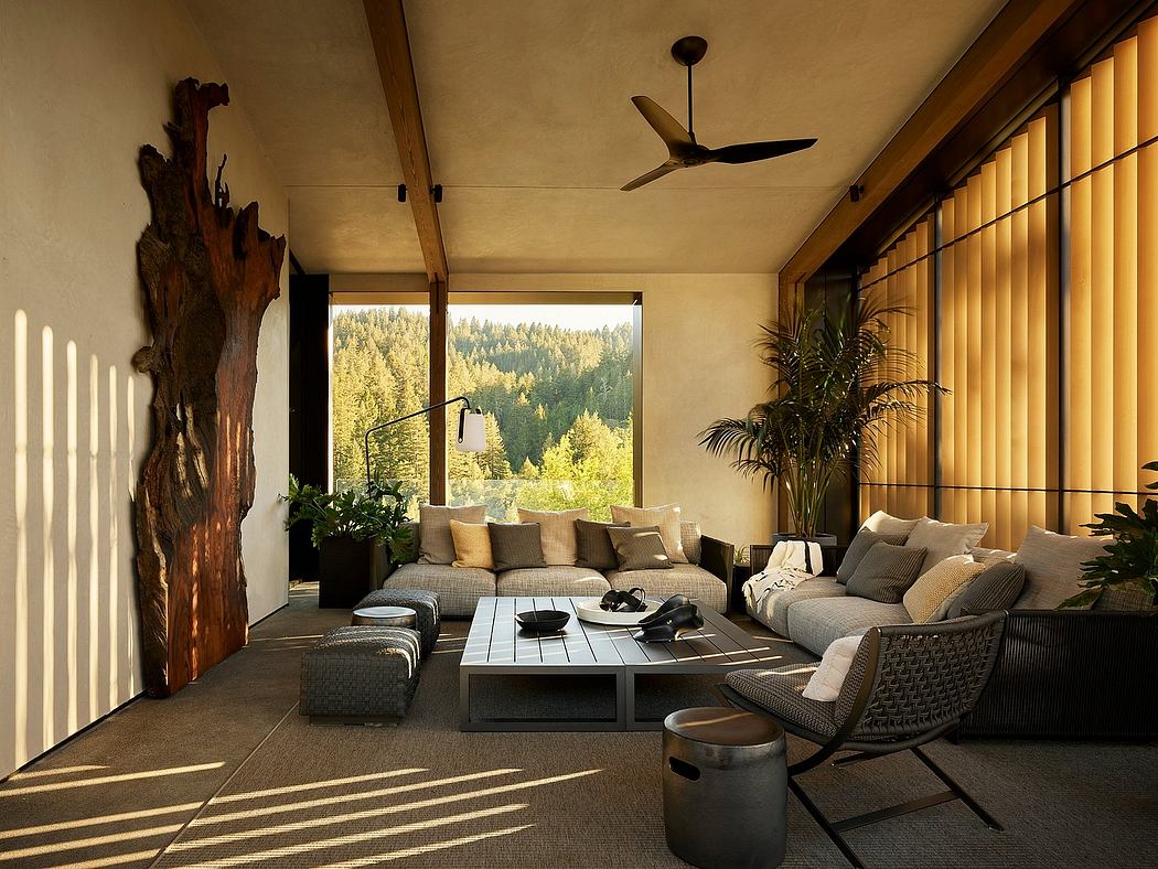 Cozy, modern living room with large windows showcasing lush forest view and warm, earthy tones.