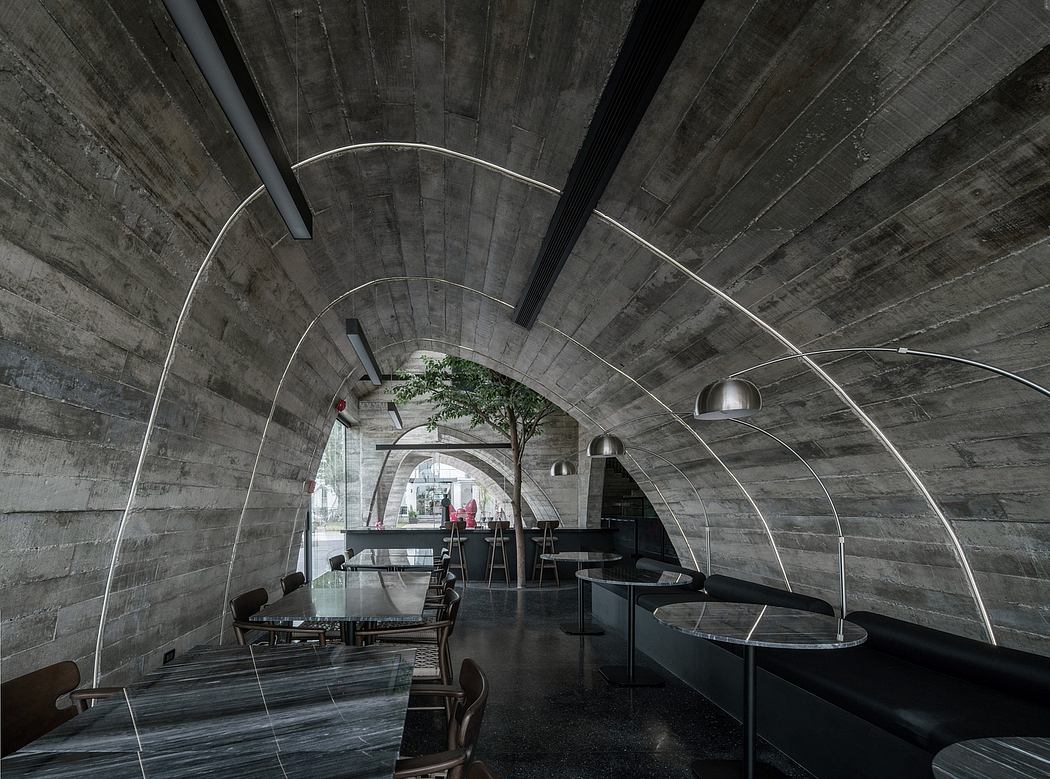 Dramatic arched concrete ceiling frames an unconventional cafe interior with modern furnishings.