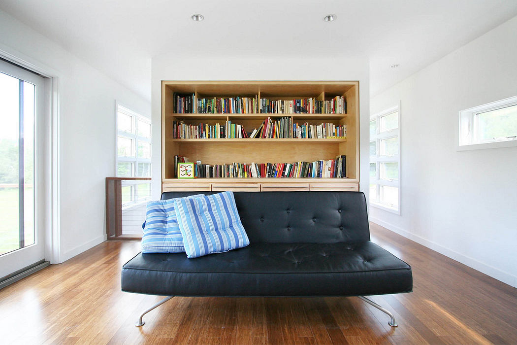A cozy room with a black leather sofa, floor-to-ceiling bookshelves, and natural light.