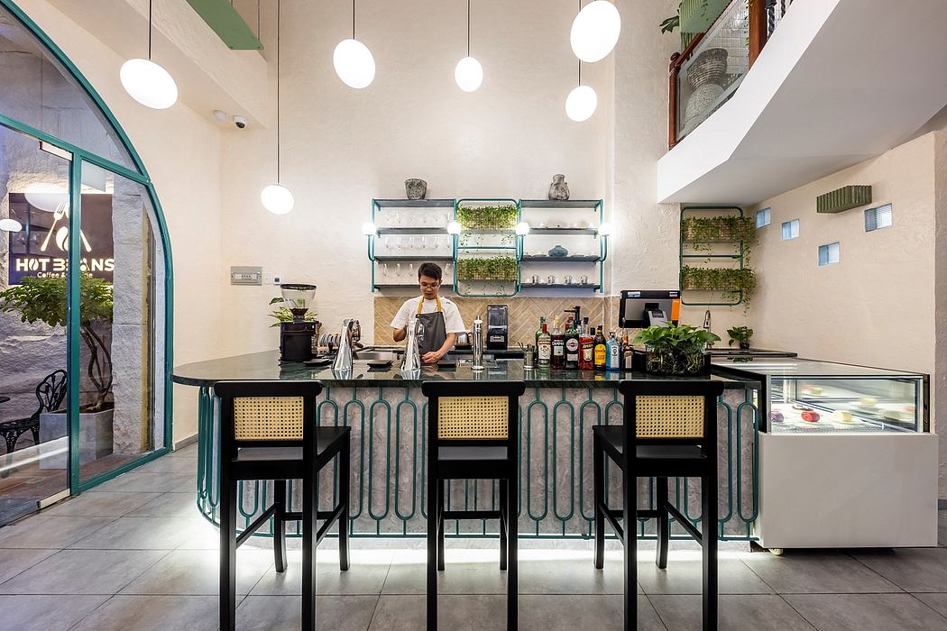 A modern cafe interior featuring a sleek bar, pendant lighting, and greenery decor.