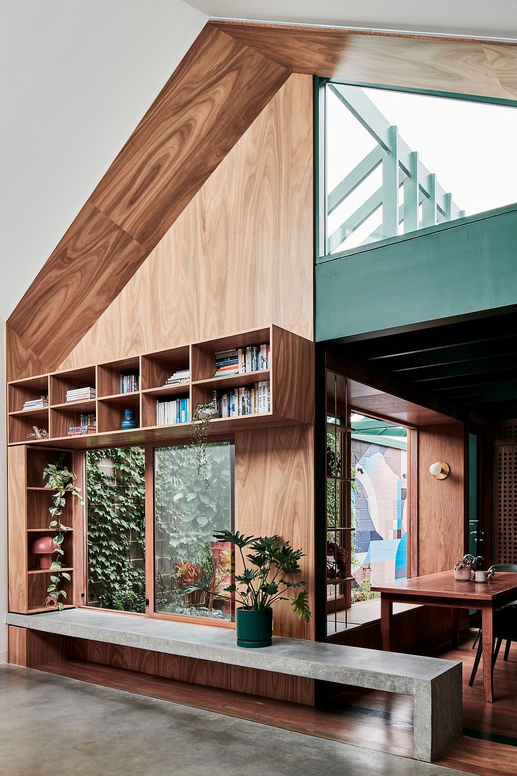 A modern, open-concept interior with a wood-paneled wall, built-in shelving, and expansive windows overlooking lush greenery.