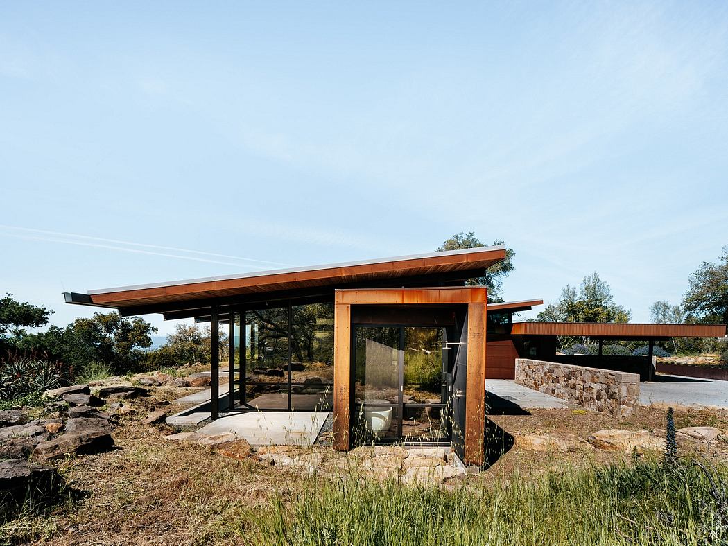 Modernist structure with wood and stone accents, integrated into natural landscape.