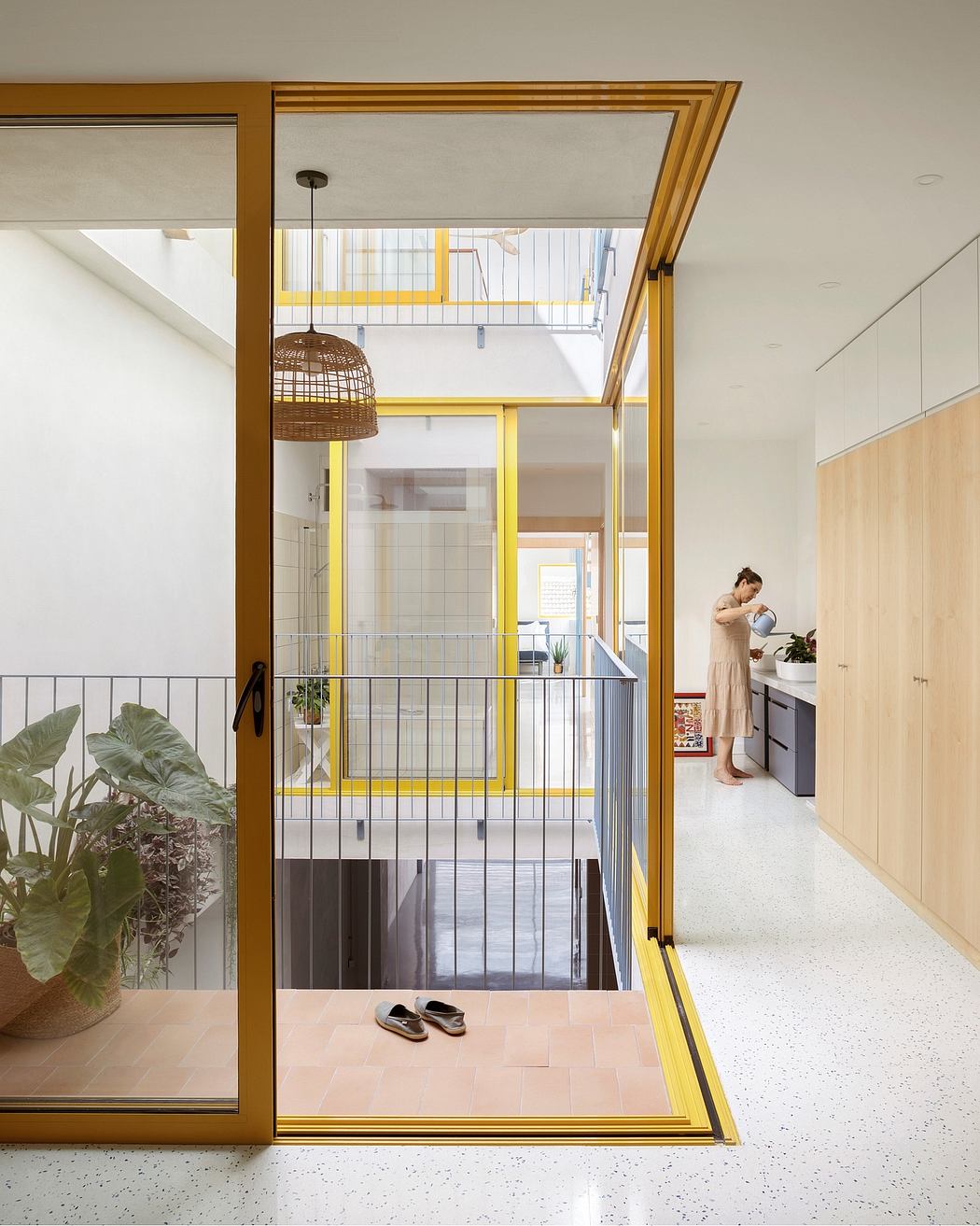 Vibrant yellow-framed glass doors open to a bright, terazzo-tiled living space.