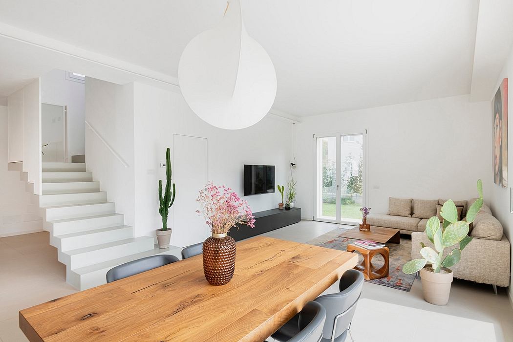 Bright, modern living room with wooden dining table, cacti, and minimalist decor.
