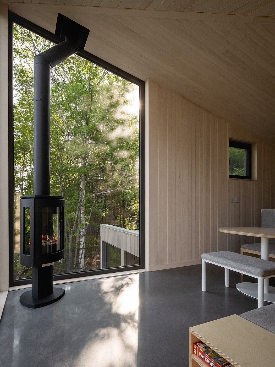 A cozy, minimalist interior with a fireplace, large windows, and natural wood accents.