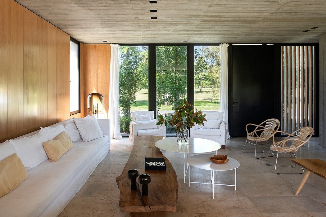 Inviting living space with wooden walls, large windows, natural furnishings, and greenery.