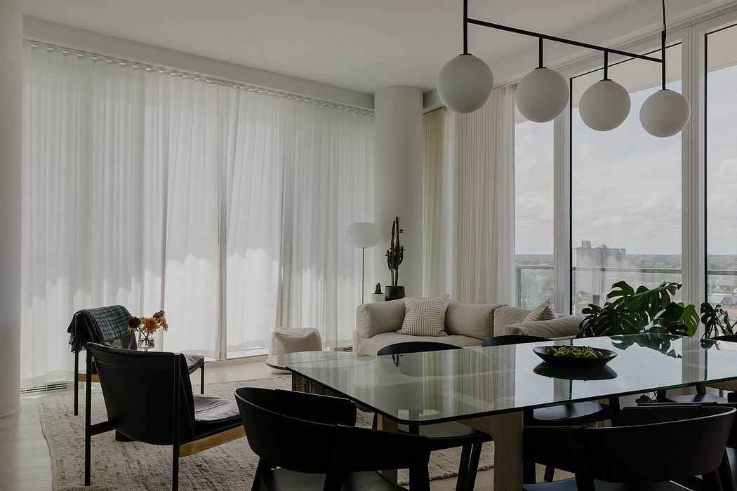 Minimalist living room with large windows, modern lighting fixtures, and glass dining table.