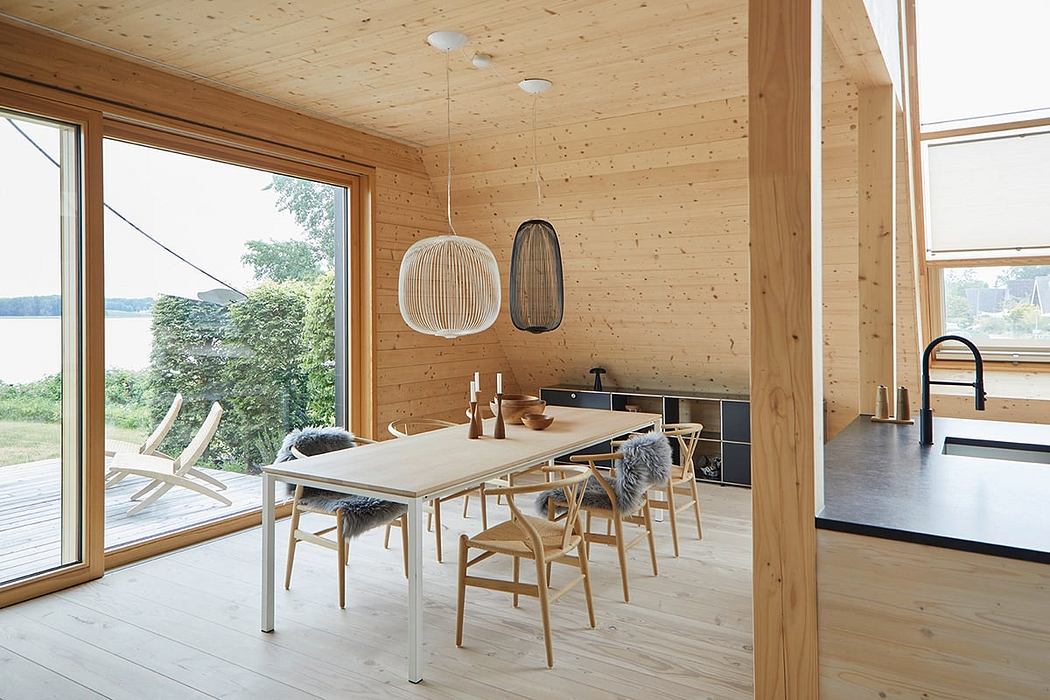Modern, wooden cabin interior with sleek dining table, minimalist lighting, and nature views.