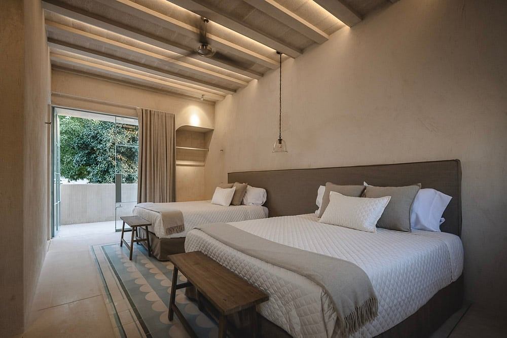 A cozy bedroom with exposed beams, neutral tones, and a sliding glass door to the outdoors.