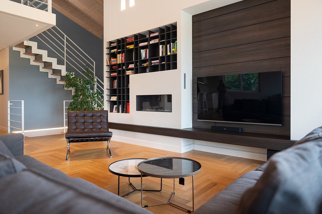 Modern, open-plan living room with sleek furniture, built-in shelving, and a TV wall.