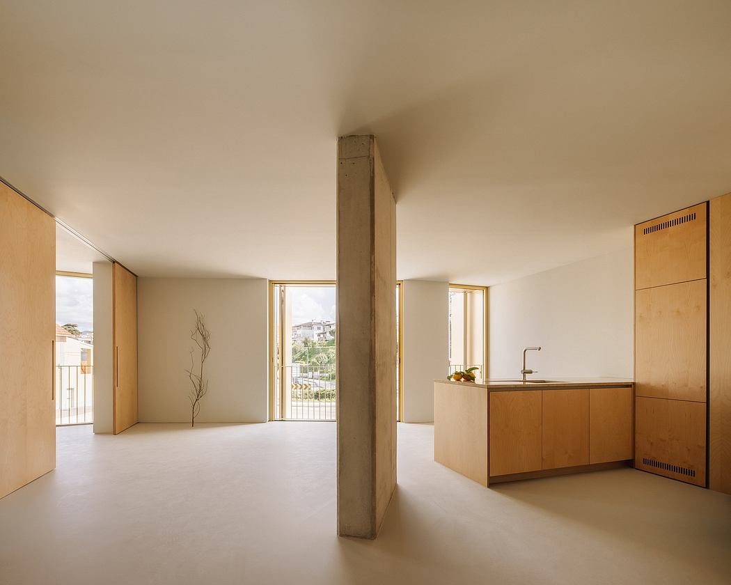 An open interior with minimalist design, large windows, and a wooden kitchen unit.