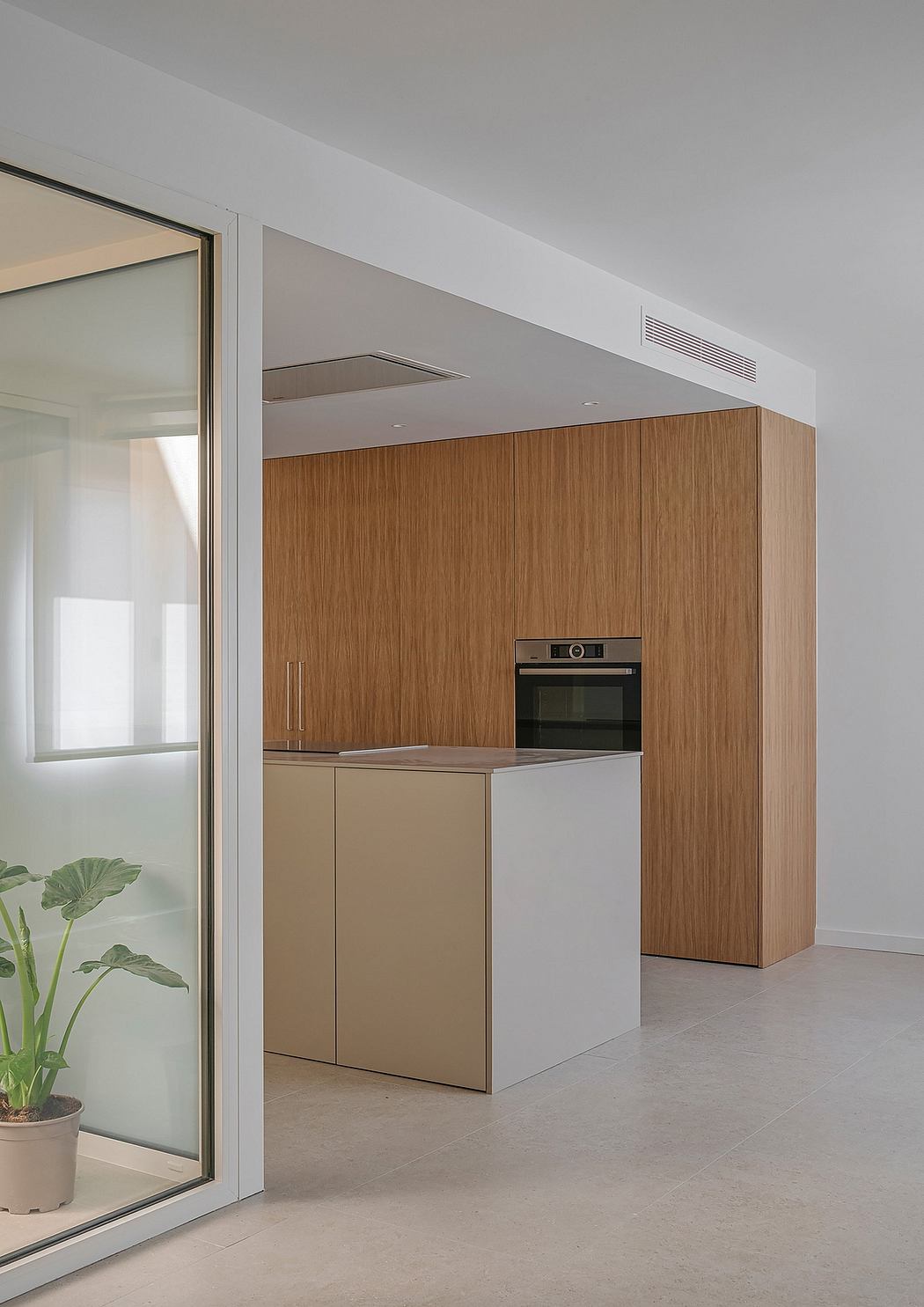 Modern kitchen with sleek wood cabinets, built-in oven, and minimalist design.