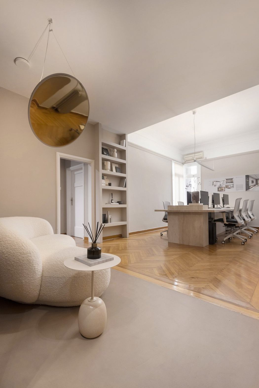A modern and airy office space with a circular mirror, wooden furniture, and ample shelving.