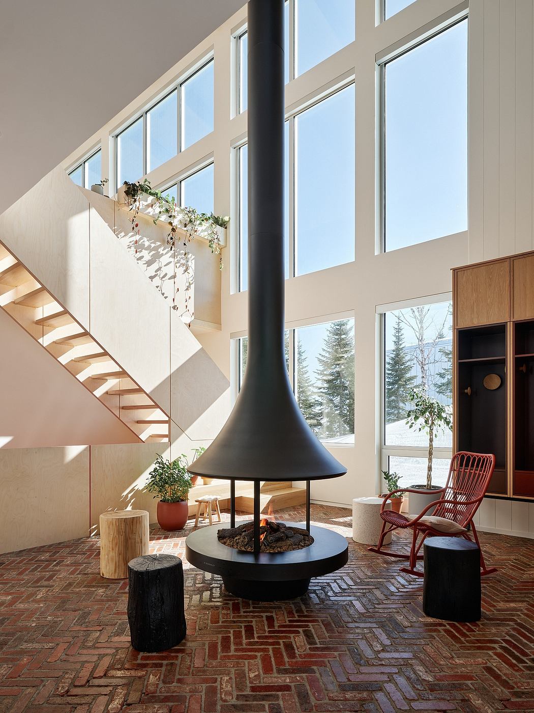 A modern, bright interior with a floor-to-ceiling fireplace and a stunning view through large windows.