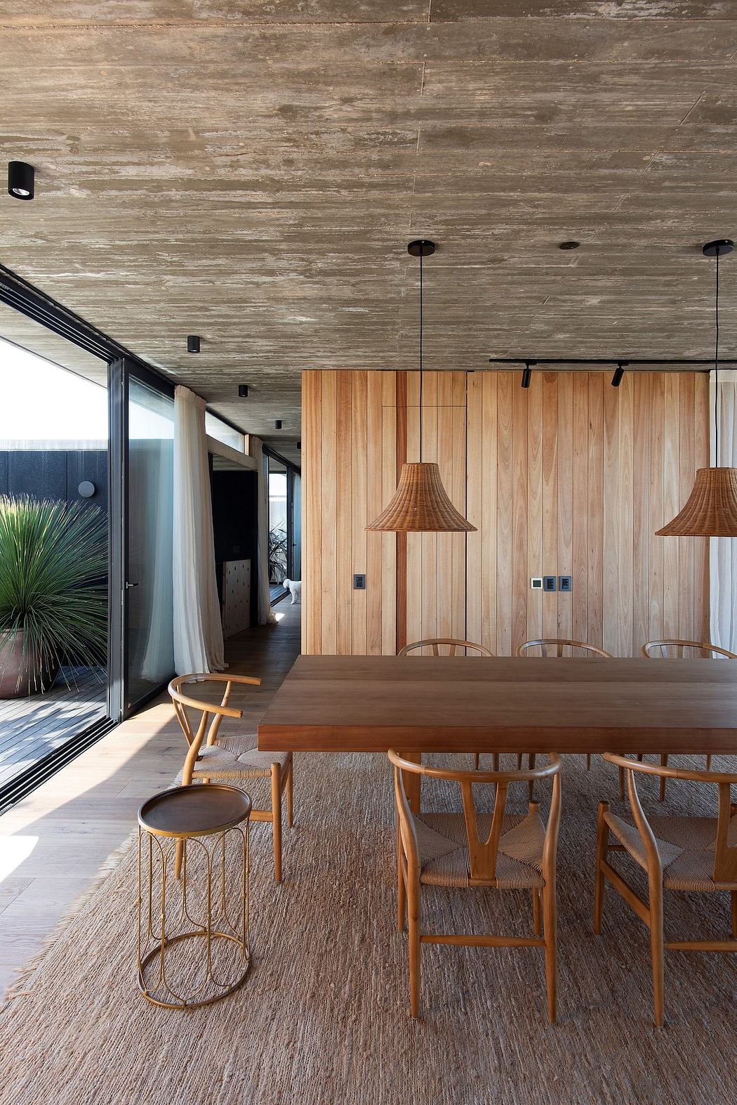Modern and spacious dining room with wooden walls, pendant lamps, and a large dining table.