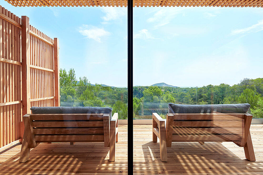 Wooden patio with cozy seating overlooking lush, scenic landscape.