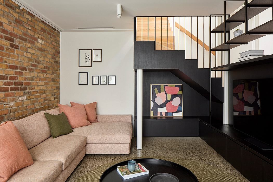 A cozy living room with brick walls, a gray sofa, and a modern staircase design.
