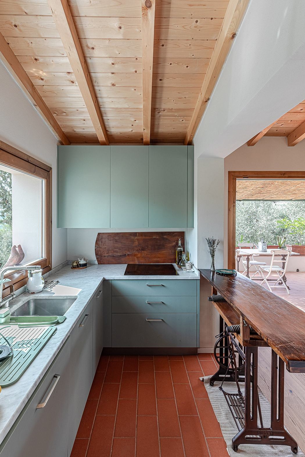 Rustic kitchen with wooden ceiling, mint green cabinets, and a wooden countertop.