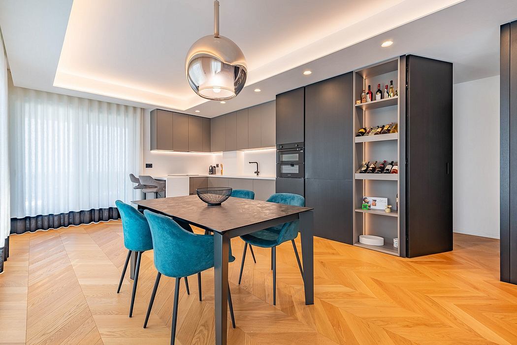 Sleek, modern kitchen with dark cabinets, hardwood floors, and a large dining table with teal chairs.