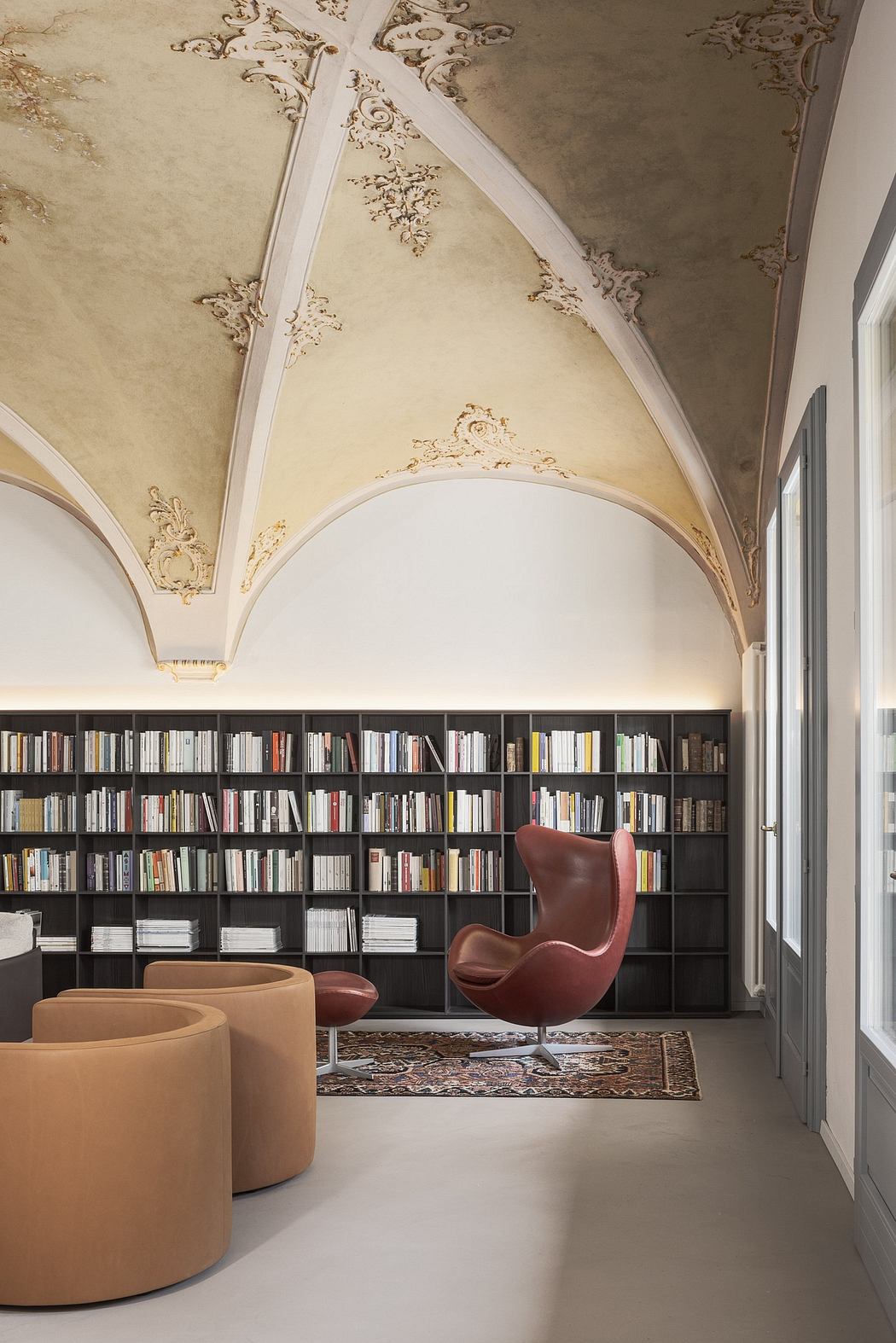 Ornate, vaulted ceiling contrasts with modern, built-in bookshelves and plush seating.
