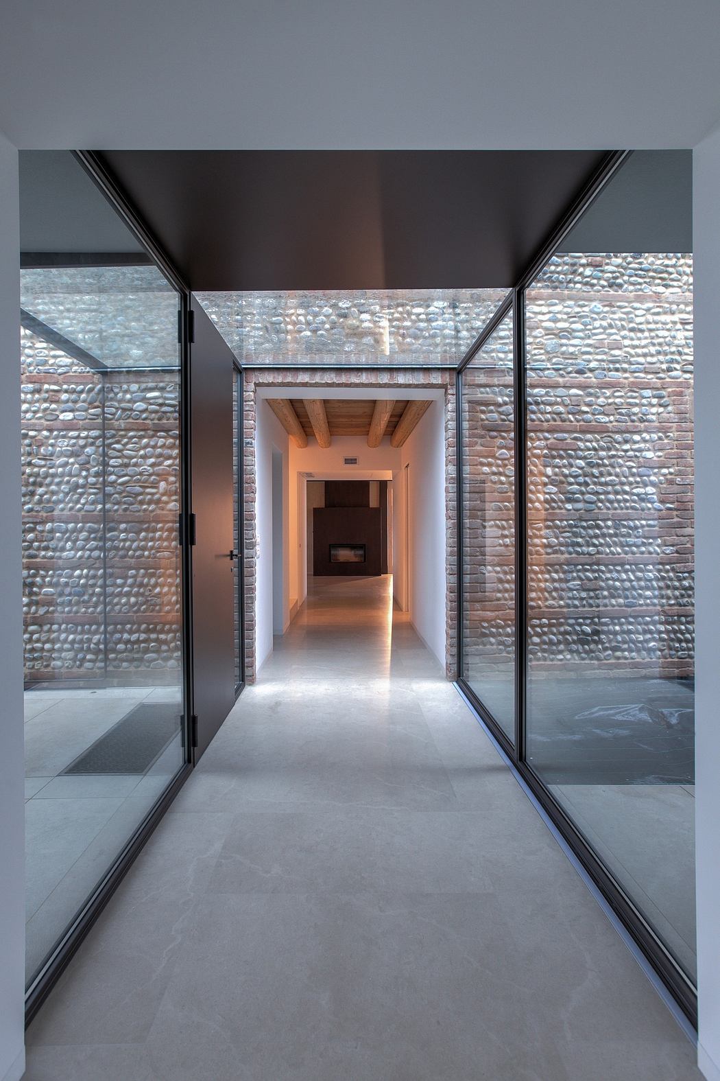 A modern interior with a brick accent wall, glass walls, and a wooden ceiling.