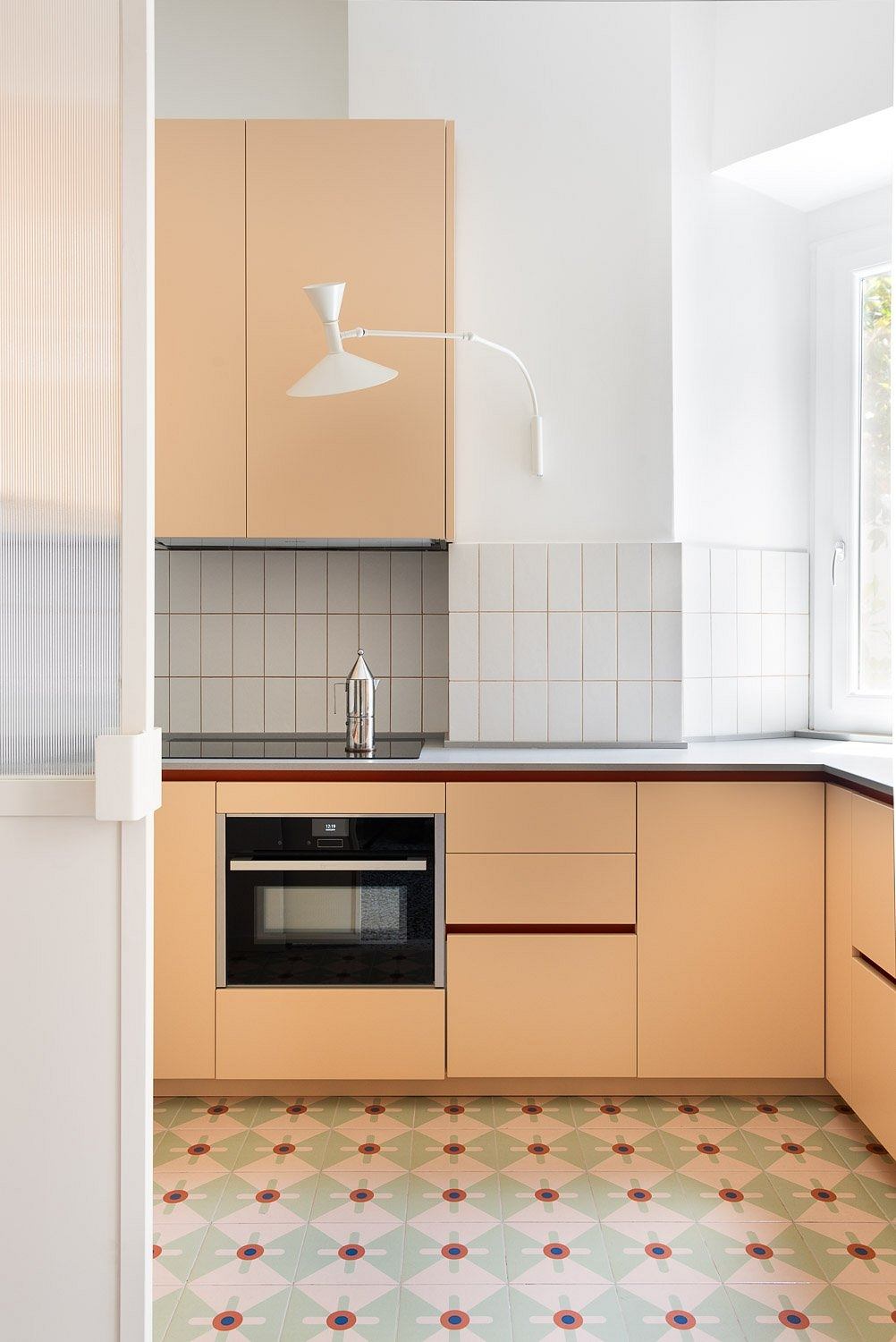 Minimalist kitchen with wood-paneled cabinets, patterned tile floor, and modern lighting.
