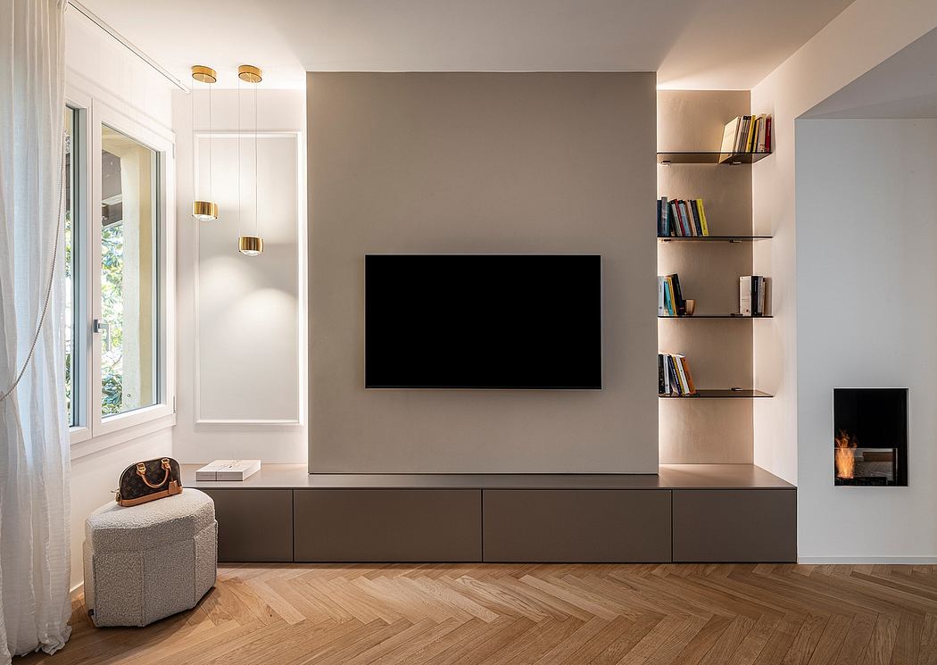 Minimalist living room with large TV, built-in shelving, and herringbone wood flooring.