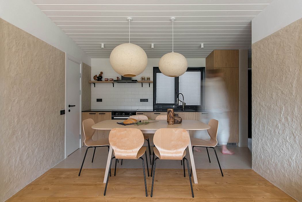 Minimalist kitchen and dining space with neutral colors, wooden furniture, and globe-shaped pendant lights.