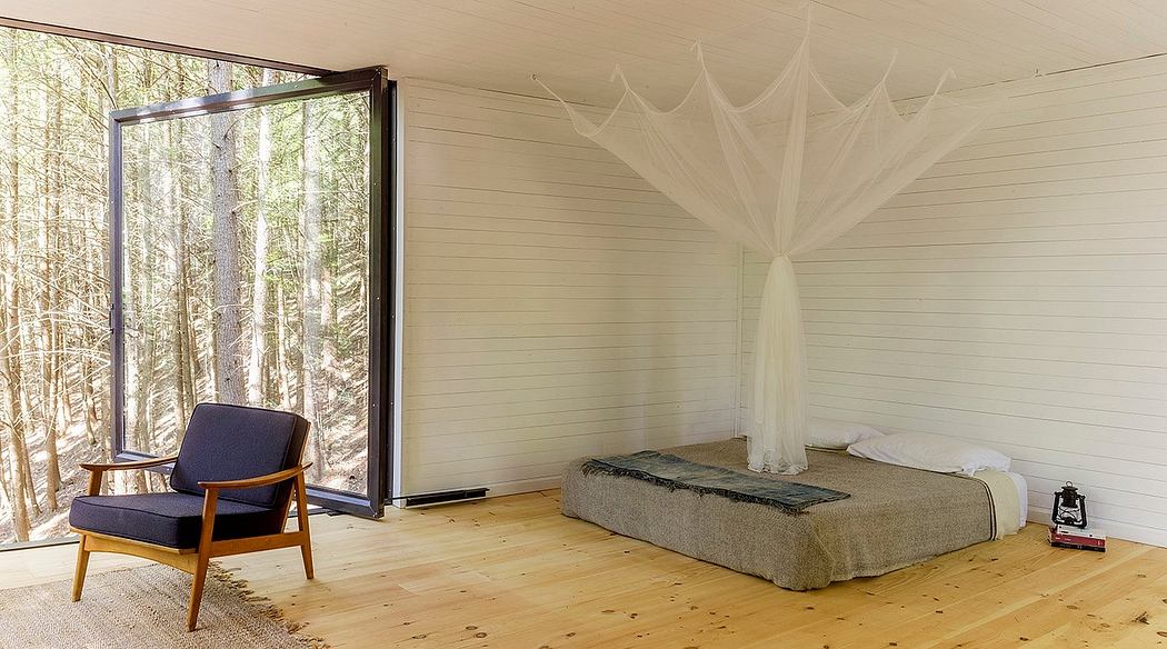 A cozy cabin bedroom with large windows, wooden paneling, and a suspended canopy bed.