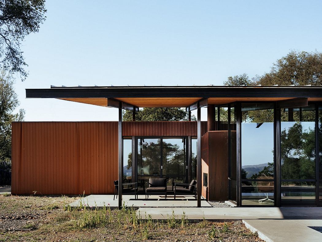 A modern, single-story home with a corrugated metal exterior, wooden accents, and expansive windows that provide scenic views.