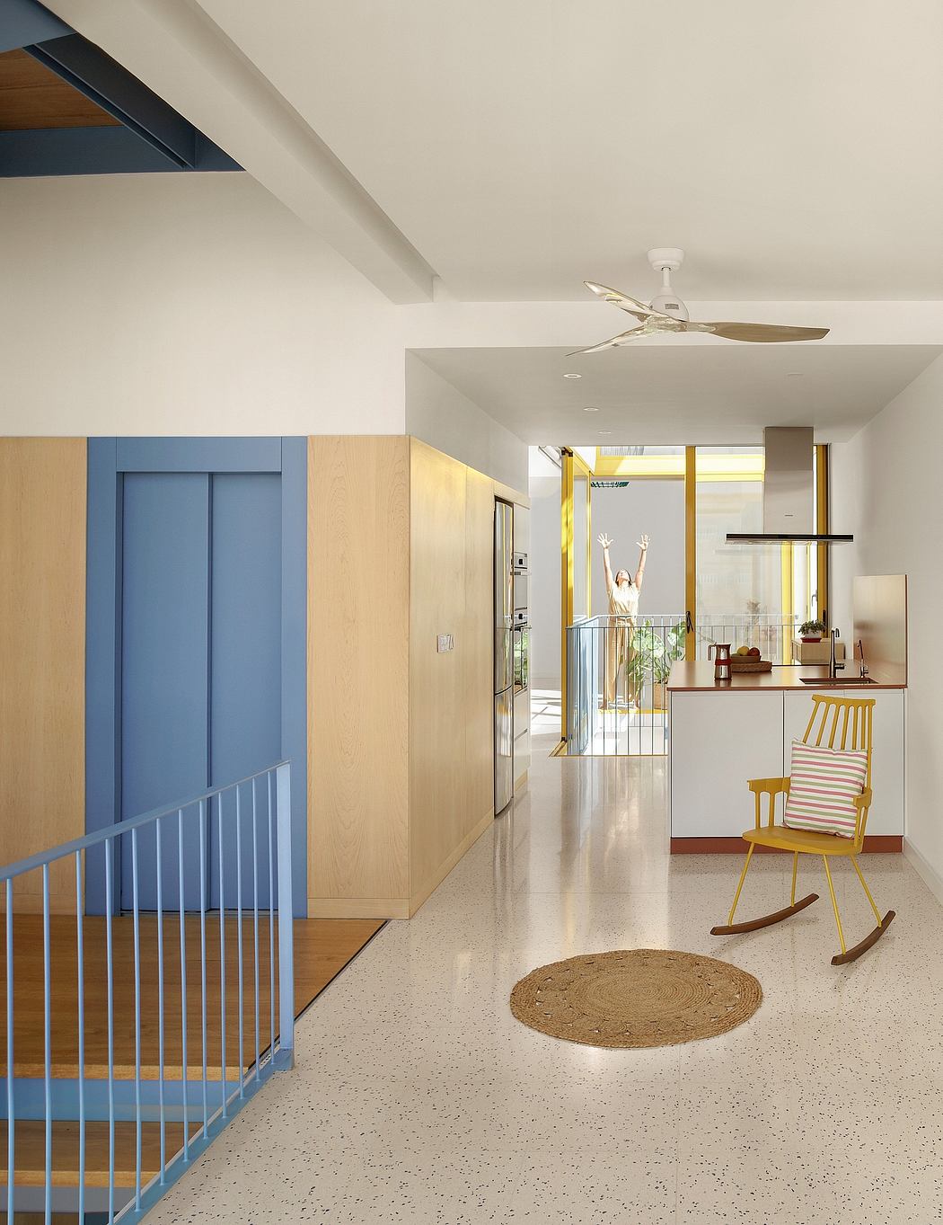 A bright, open-plan interior with a modern ceiling fan, colorful accents, and a terrace.