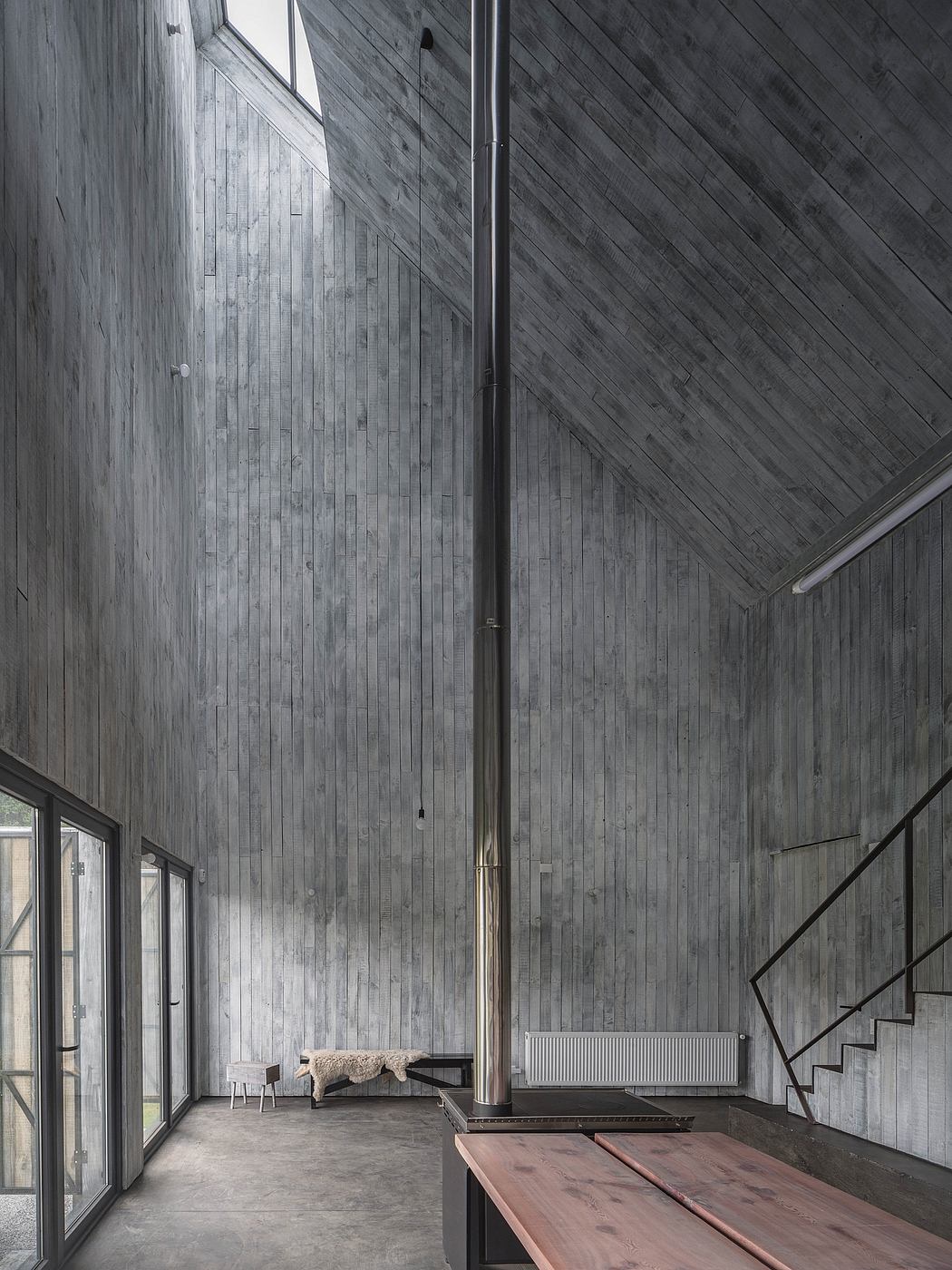 A rustic interior with wooden walls, sleek furniture, and a central chimney as the focal point.