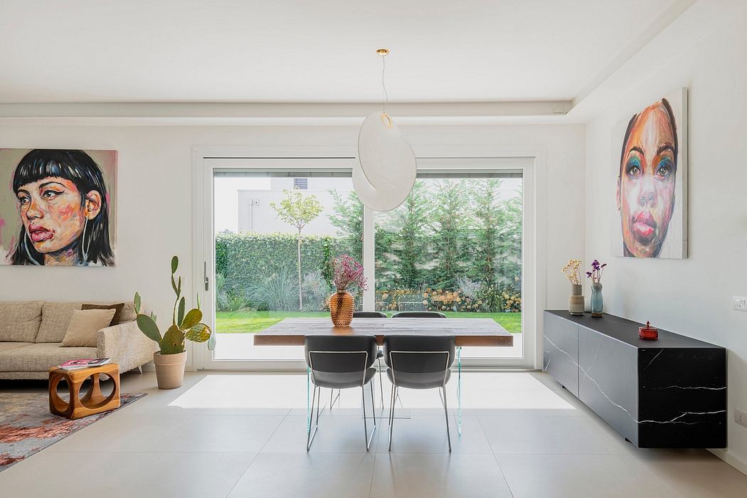 Bright, airy room with large window overlooking lush garden, modern furnishings, and colorful artwork.