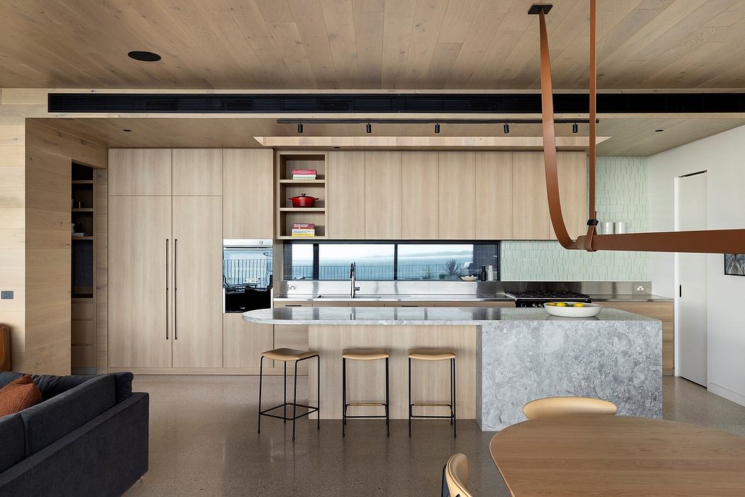 Modern kitchen with wood-paneled cabinetry, marble island, and sleek lighting fixtures.