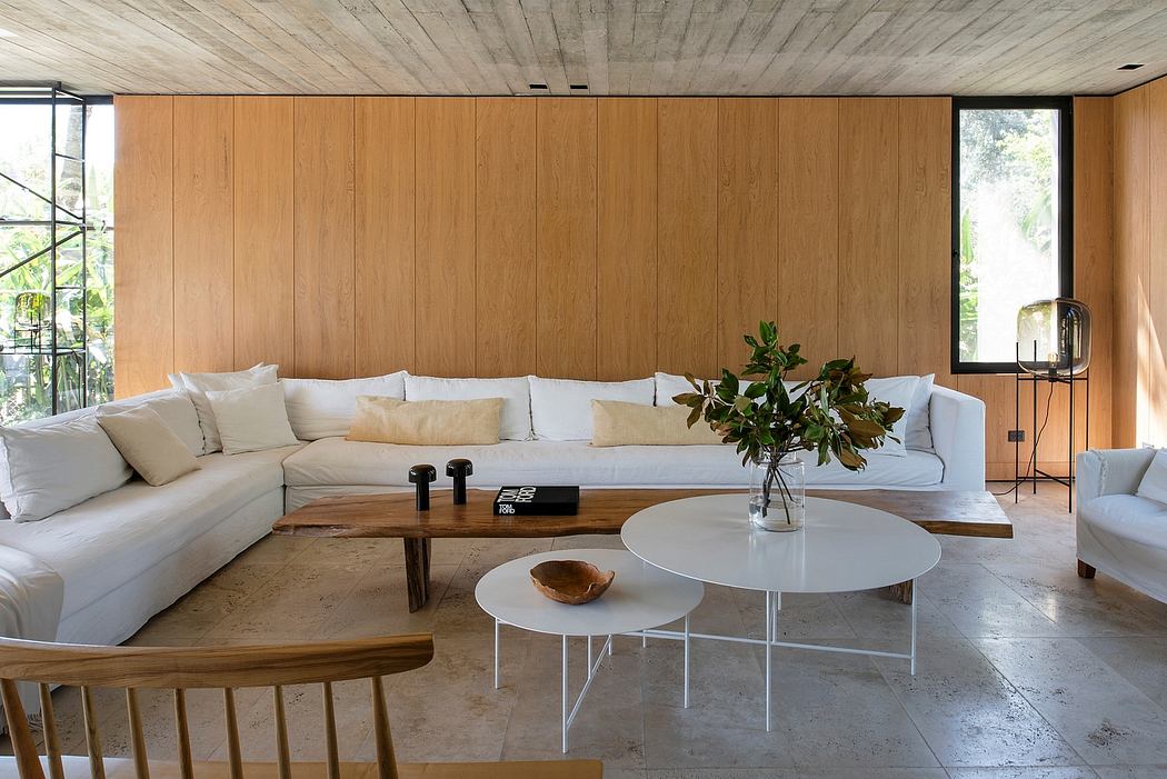 Minimalist living room with wooden walls, white couch, and modern coffee tables.