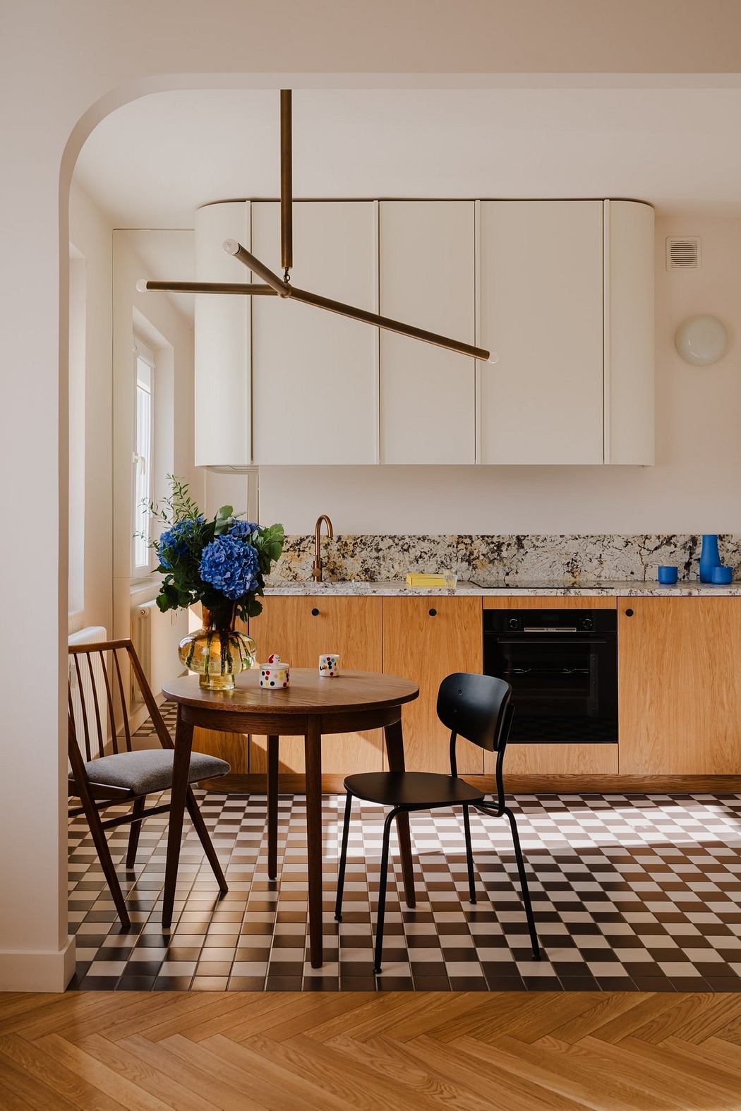 Modern kitchen with sleek wooden cabinets, pendant lighting, and a checkered tile floor.