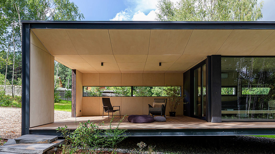 A modern, minimalist house with an open-plan interior, large windows, and a deck overlooking a garden.