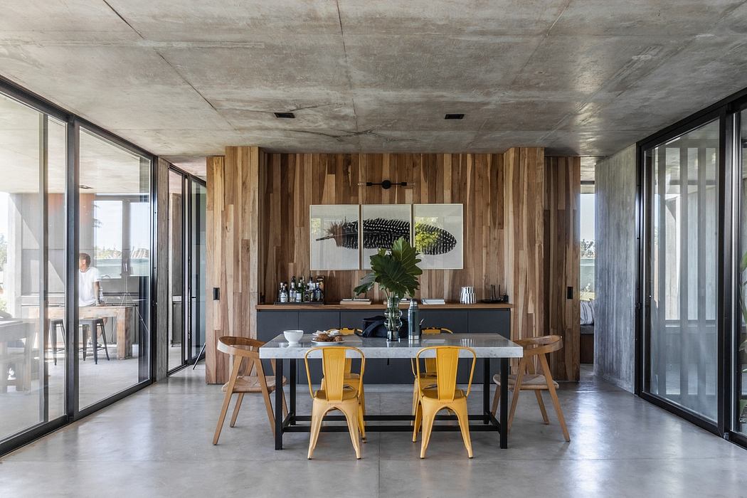 Contemporary open-plan dining area with wood-paneled walls, industrial-style table, and sleek furnishings.