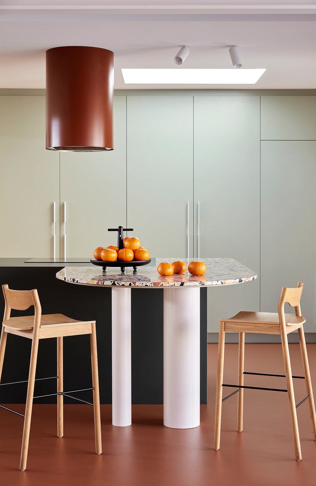Modern kitchen with stylish pendant light, round marble table, and minimalist wooden chairs.