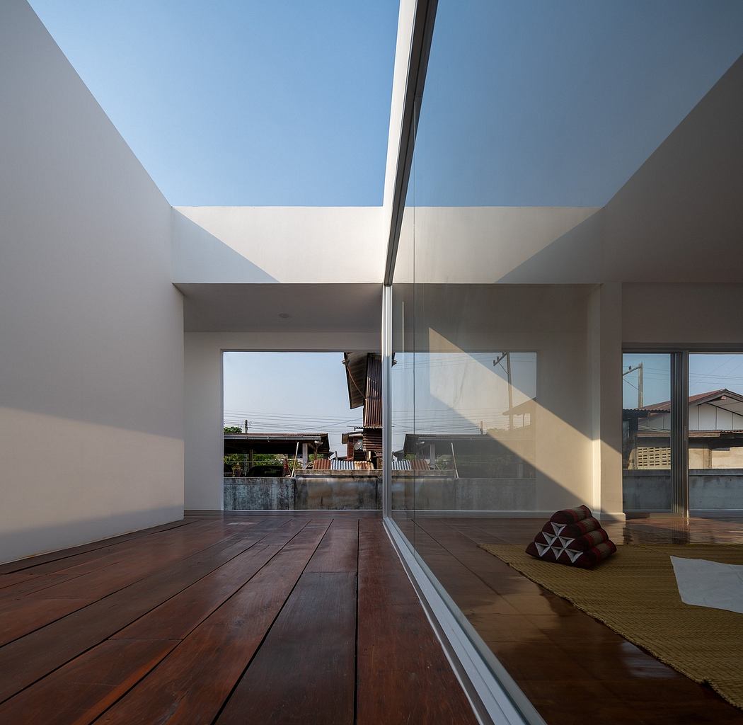 Minimalist interior design with large skylights, wooden floors, and a decorative cushion.