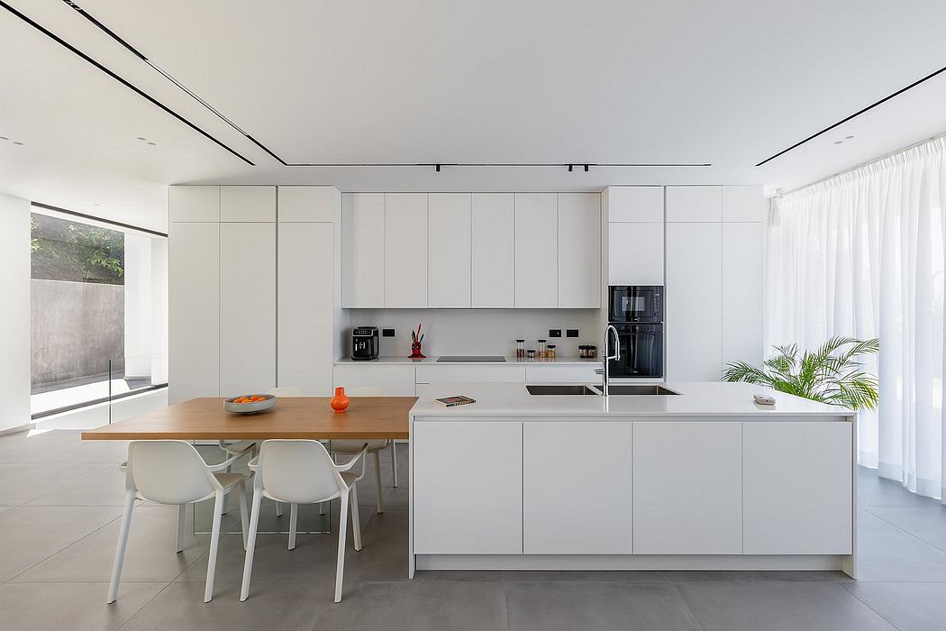 Sleek, minimalist kitchen with wooden dining table, white cabinetry, and large windows.